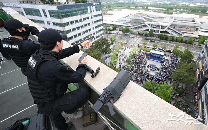 이재명 더불어민주당 대선 후보가 20일 경기 파주시 금릉역 광장에서 유세를 하고 있는 가운데 경찰 특공대가 제밍건을 옆에 두고 경계 근무를 서고 있다.