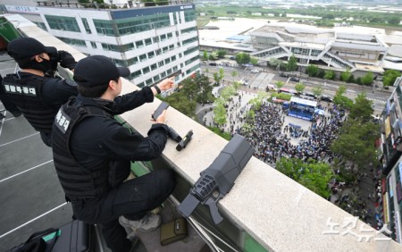 이재명 더불어민주당 대선 후보가 20일 경기 파주시 금릉역 광장에서 유세를 하고 있는 가운데 경찰 특공대가 제밍건을 옆에 두고 경계 근무를 서고 있다.
