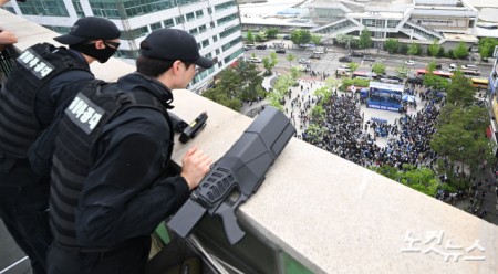 이재명 더불어민주당 대선 후보가 20일 경기 파주시 금릉역 광장에서 유세를 하고 있는 가운데 경찰 특공대가 제밍건을 옆에 두고 경계 근무를 서고 있다.