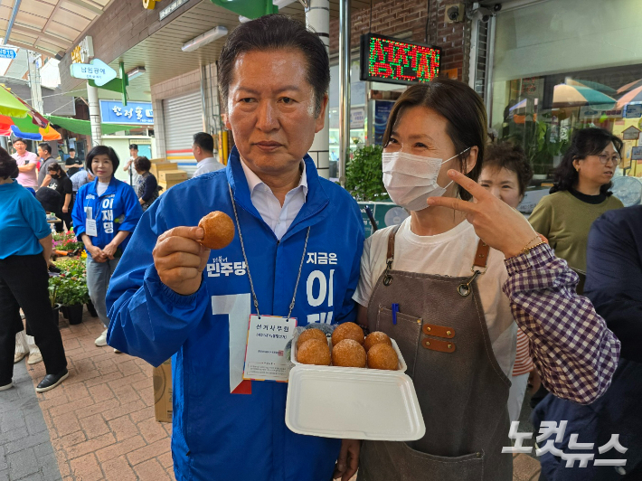 정청래 의원이 웃장에서 상인과 함께 도너츠를 들고 기념촬영하고 있다. 고영호 기자