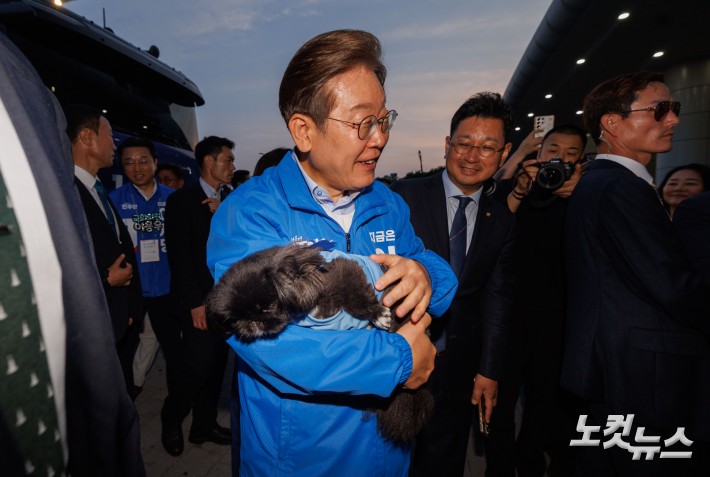 이재명 더불어민주당 대선후보가 21일 오후 인천 계양역 유세를 마치고 떠나던 중 한 지지자의 강아지를 안아보고 있다.