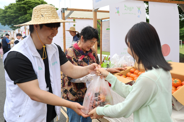 현대위아의 한 직원이 지난 21일 경상남도 창원특례시 현대위아 본사에서 열린 '이음마켓'에서 지역 농가의 농산물을 사고 있다. 현대위아 제공