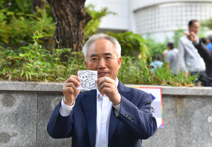 더불어민주당 광주선거대책위원회 양부남 위원장이 29일 광주 서구문화센터 사전투표소에서 선대위 관계자 60여명과 함께 단체로 사전투표하고 투표 인증용지를 들어보이고 있다. 더불어민주당 광주시당 제공
