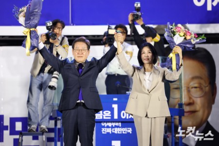 제21대 대통령 당선이 확실시되는 더불어민주당 이재명 대선 후보와 김혜경 여사가 4일 서울 여의도 국회 앞에 마련된 더불어민주당 국민 개표방송 행사에서 꽃다발을 받은 뒤 인사하고 있다.