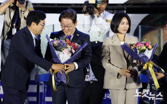 제21대 대통령 당선이 확실시되는 더불어민주당 이재명 대선 후보가 4일 서울 여의도 국회 앞에 마련된 더불어민주당 국민 개표방송 행사에서 꽃다발을 받고 있다.