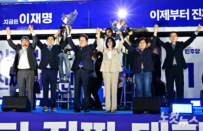 제21대 대통령 당선이 확실시되는 더불어민주당 이재명 대선 후보와 김혜경 여사를 비롯한 박찬대 상임총괄선대위원장, 정은경·김경수·김동명 상임선대위원장이 4일 서울 여의도 국회 앞에 마련된 더불어민주당 국민 개표방송 행사에서 손을 들어올리고 있다. 류영주 기자
