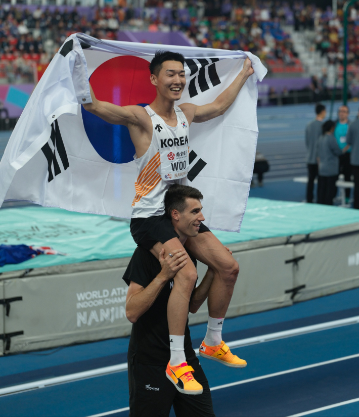 우상혁이 지난 3월 21일 중국 난징에서 열린 2025 세계실내육상선수권대회 남자 높이뛰기 결선에서 우승한 뒤, 2위 해미시 커 목에 올라타 기념촬영하고 있다. 용인시청 육상팀 제공
