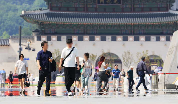 9일 서울 광화문 광장에서 시민과 관광객들이 뜨거워진 광장위를 걷고 있다. 연합뉴스