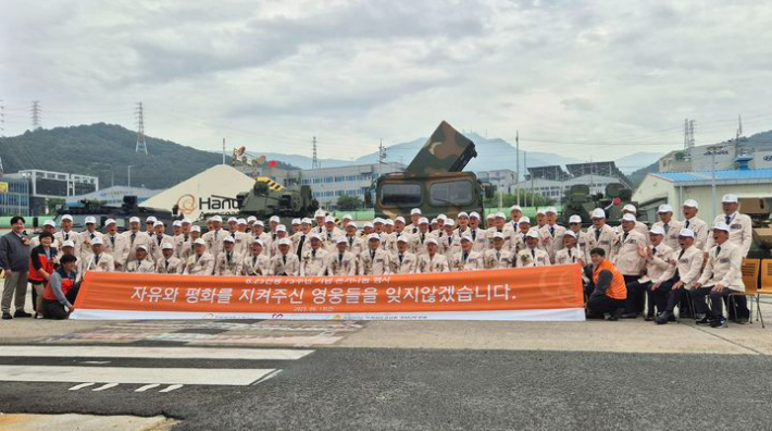 한화에어로스페이스가 6∙25전쟁 75주년을 맞아 6∙25 참전유공자들을 지난 13일 창원사업장으로 초청한 가운데 참전유공자들이 성능시험 관람을 마치고 전시장비 앞에서 단체 기념사진 촬영을 하고 있다. 한화에어로스페이스 제공