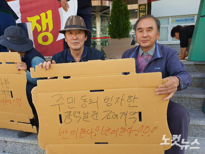 지난해 10월 기자회견 당시 주민들이 반대 피켓을 들고 있다. 고영호 기자