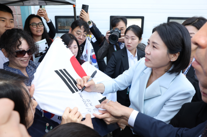 G7 정상회의에 참석하는 이재명 대통령과 함께 캐나다를 방문한 김혜경 여사가 17일(현지시간) 캘거리 한인회관에서 환영나온 주민들의 요청에 태극기에 서명하고 있다. 연합뉴스