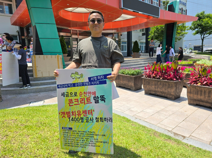 류정호 순천환경운동연합 이사가 순천시 앞에서 '갯벌치유센터 건립 공사 철회' 피켓을 들고 있다. 고영호 기자