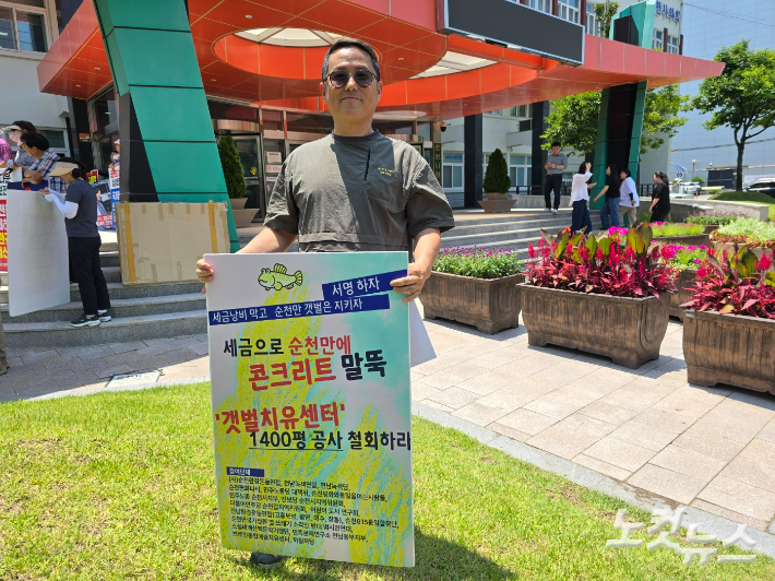 류정호 순천환경운동연합 이사가 순천시 앞에서 '갯벌치유센터 건립 공사 철회' 피켓을 들고 있다. 고영호 기자