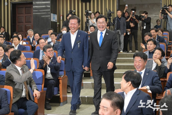 더불어민주당 당대표 출마를 선언한 정청래·박찬대 의원이 24일 서울 여의도 국회에서 열린 당 의원총회에 손을 잡고 참석하고 있다.
