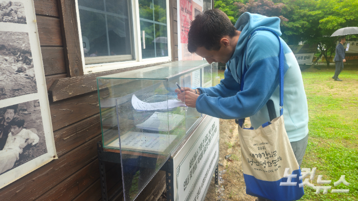 평화 순례에 참석한 한 청년이 대전 산내 민간인 학살 희생자 화장에 반대하는 서명을 하고 있다. 송주열 기자