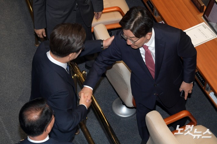 이재명 대통령이 26일 서울 여의도 국회에서 열린 본회의에서 2025년도 제2회 추가경정예산안에 대한 정부의 시정연설을 마치고 회의장을 나서며 국민의힘 권성동 의원과 인사를 하고 있다.