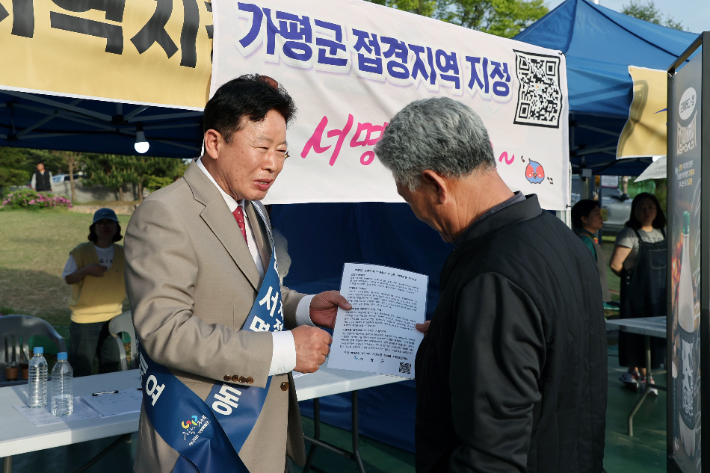 서태원 군수가 지난해 실시한 '범군민 서명운동'에서 주민으로부터 접경지역 서명을 받고 있다. 가평군 제공