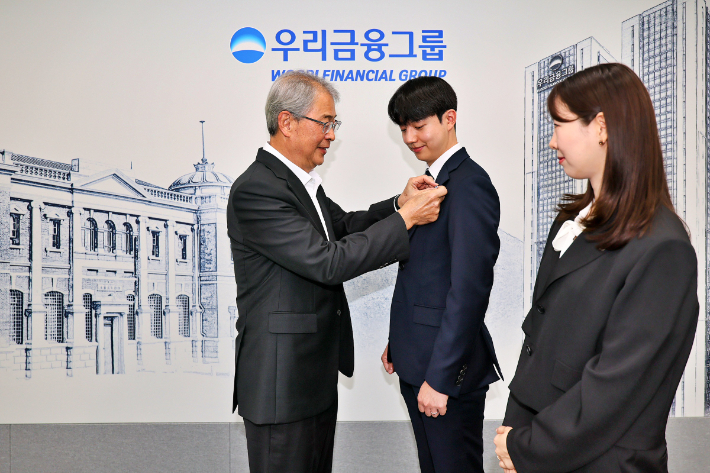 우리금융그룹 임종룡 회장이 그룹의 새 가족이 된 동양생명·ABL생명 직원에게 디지털 선도의 의미가 담긴 새로운 그룹 보조휘장을 달아주고 있다. 우리금융그룹 제공