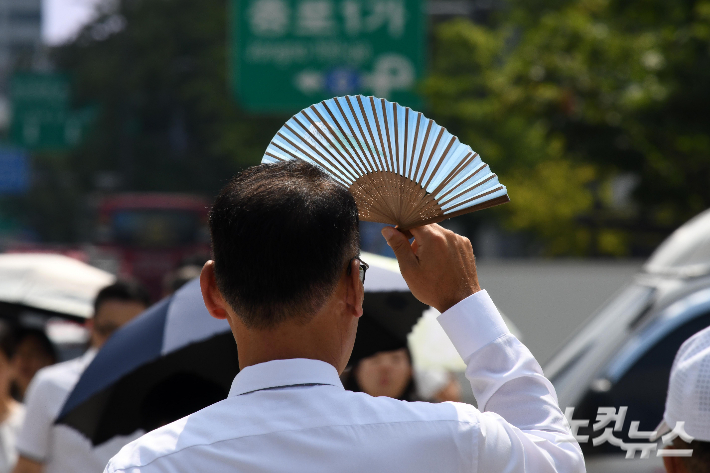 한 시민이 부채로 얼굴을 가리고 있다. 박종민 기자