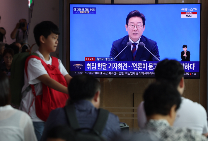 이재명 대통령의 첫 기자회견이 진행된 3일 중구 서울역에서 시민들이 방송을 지켜보고 있다. 연합뉴스