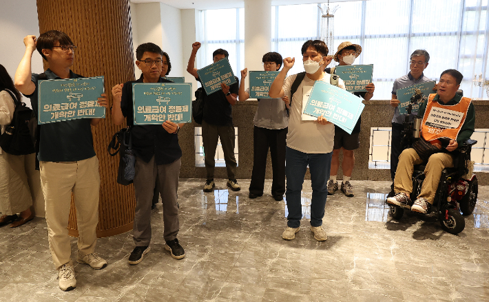 10일 서울 용산구 전쟁기념관 피스앤파크 컨벤션에서 열린 '의료급여 제도개선 시민단체' 간담회에서 시민단체 측 참석자들이 항의를 위해 퇴장한 뒤 구호를 외치고 있다. 연합뉴스