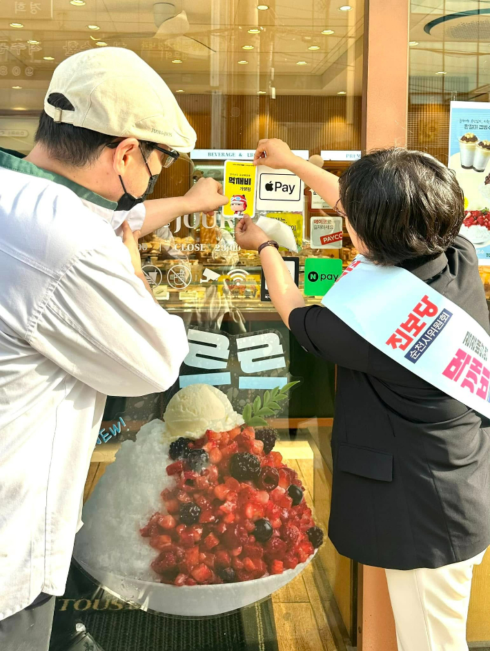 최미희 의원(우측)이 순천지역 매장에 먹깨비 가맹점 스티커를 부착하고 있다. 최미희 의원 제공