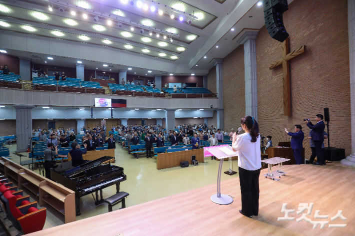 참석자들이 일어서서 주제를 제창하고 있다.