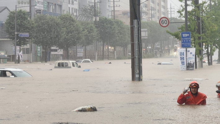 지난 17일 오후 집중호우로 광주 북구 신안동을 흐르는 서방천이 범람하면서 인근 도로가 완전히 침수됐다. 구조대원들이 차량이 물에 잠긴 도심 한복판에서 구조 작업을 벌이고 있다. 독자 제공