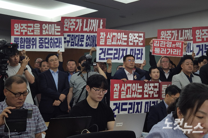 김관영 전북도지사의 전입신고 절차 이후 이어진 김 지사와 더불어민주당 정동영 국회의원, 이성윤 국회의원, 우범기 전주시장의 기자회견에서도 완주군의회 의원들이 반대 팻말을 들고 항의하고 있다. 송승민 기자