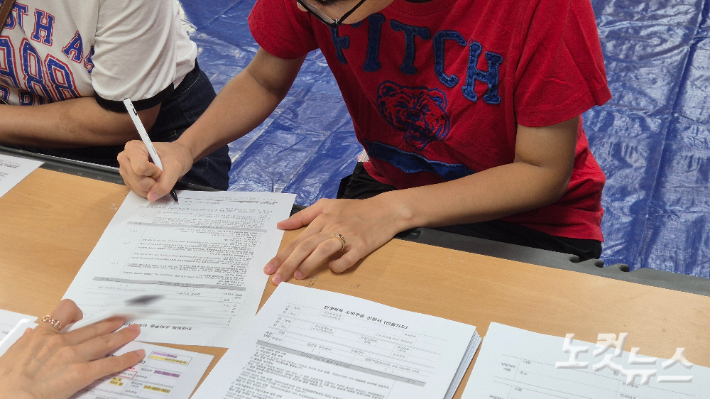 21일 오전 9시쯤 한 시민이 민생회복 소비쿠폰 신청서를 작성하고 있다. 한아름 기자