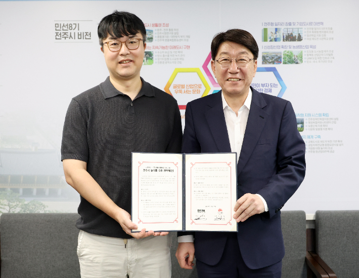 우범기 전주시장(오른쪽)과 김완엽 DI VINA F&B 그룹 대표가 22일 지역 농식품 수출에 대한 협약서를 들고 기념 촬영을 하고 있다. 전주시 제공