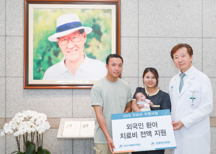 유창식 강릉아산병원장과병원장과 환아의 가족이 고(故) 정주영 아산사회복지재단 설립자의 사진 앞에서 기념 촬영을 하고 있다. 강릉아산병원제공