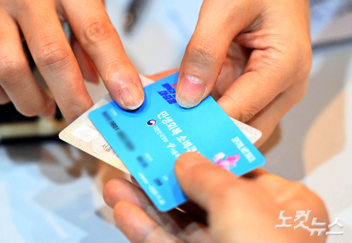 민생회복 소비쿠폰 신청이 시작된 21일 서울 동작구 대방동주민센터 작은도서관에서 시민들이 신청한 선불카드를 받고 있다. 황진환 기자