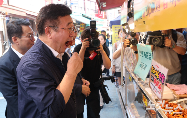 정부의 '민생회복 소비쿠폰' 정책이 시행중인 24일 윤호중 행정안전부 장관이 소비쿠폰 사용처인 서울 금천구 비단길 현대시장의 한 닭강정집을 방문, 구매 전 시식을 하고 있다. 황진환 기자