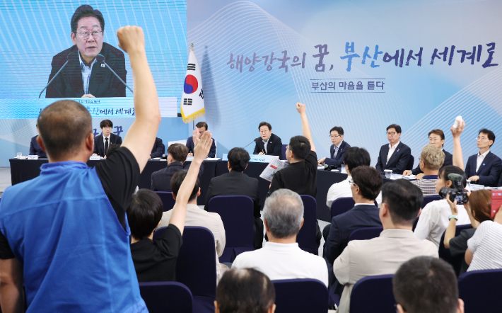 윤병철 대한민국공무원노동조합총연맹 해양수산부지부 위원장(왼쪽 파란 조끼)이 25일 부산 부경대에서 이재명 대통령이 참석한 가운데 열린 타운홀미팅 '부산의 마음을 듣다' 간담회에서 손을 들어 발언권을 요청하고 있다. 연합뉴스