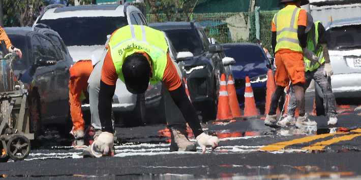 폭염이 이어진 31일 대구 수성구 수성못오거리에서 노동자들이 달궈진 도로에서 차선 도색 작업을 하고 있다. 연합뉴스