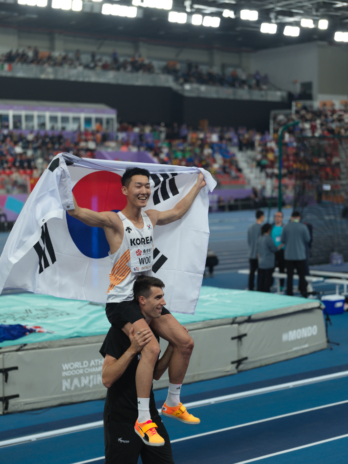 우상혁이 지난 5월 21일 중국 난징에서 열린 2025 세계실내육상선수권대회 남자 높이뛰기 결선에서 우승한 뒤, 2위 해미시 커 목에 올라타 기념촬영하고 있다. 용인시청 육상팀 제공