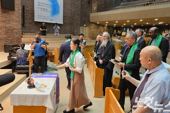 에큐메니칼 공동체 구성원들이 화해와 통일의 상징물을 들고 입장하고 있다. 개신교와 가톨릭 공동으로 번역한 남측 성경, 북측교회가 실제로 사용하는 북측 성경, 각기 다른 나무들로 만들어진 '한 몸 십자가', 물과 흙이 원래 하나이듯 분단의 아픔이 치유되길 바라는 '물과 흙'이 놓여졌다.