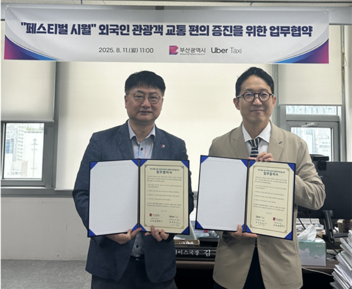 부산시 김현재 관광마이스국장(왼쪽)과 송진우 우버 택시코리아 총괄(오른쪽)이 업무협약서에 서명했다. 부산시 제공