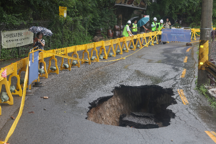 서울 곳곳에 호우주의보가 내린 13일 집중호우로 인한 땅 꺼짐 현상이 발생한 서울 강북구 도선사 진입로에 시민들의 접근을 막는 펜스가 설치돼 있다. 연합뉴스