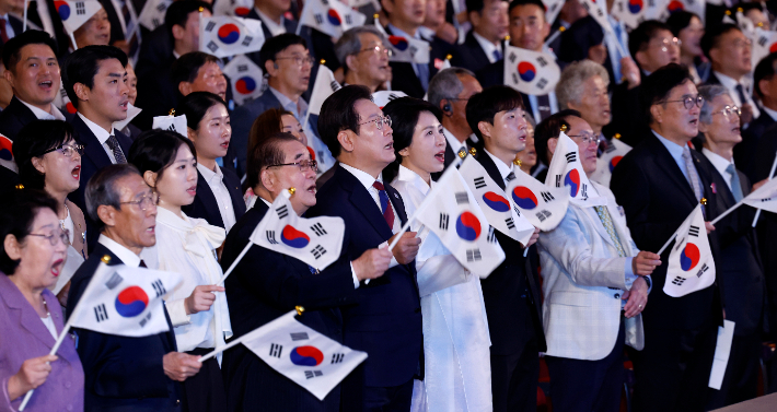 이재명 대통령과 김혜경 여사가 15일 서울 세종문화회관에서 열린 80주년 광복절 경축식에서 참석자들과 함께 태극기를 흔들며 광복절 노래를 제창하고 있다. 연합뉴스