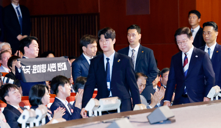 국민의힘 안철수 의원이 15일 서울 세종문화회관에서 열린 80주년 광복절 경축식에서 이재명 대통령이 경축사를 마치고 자리를 향할 때 '조국·윤미향 사면 반대'라는 문구가 적힌 펼침막을 들어보이고 있다. 연합뉴스