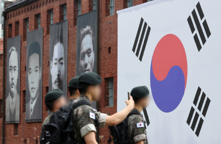 80주년 광복절을 하루 앞둔 14일 서울 서대문형무소역사관 외벽에 걸린 독립운동가들 사진 아래로 군장병들이 이동하고 있다. 연합뉴스