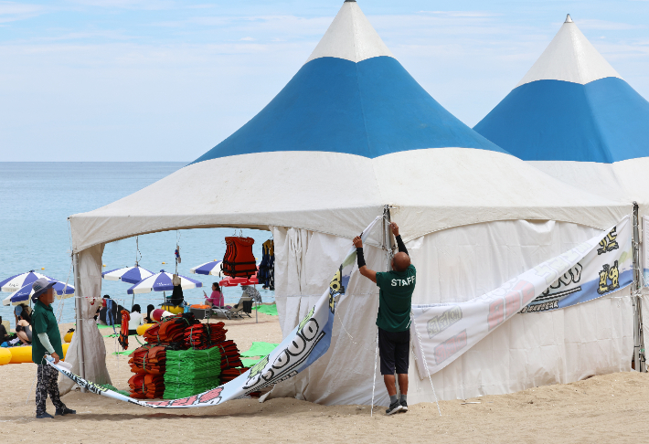 지난 17일 폐장한 경포해수욕장에서 물놀이 기구를 대여하는 상인들이 가격표가 붙은 현수막을 제거하고 있다. 연합뉴스