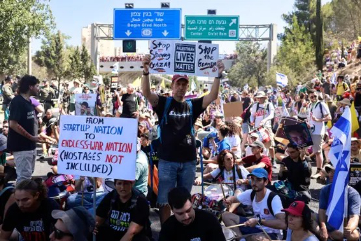 도로를 점거한 이스라엘 시위대 중 한 남성이 'Stop Starving Gaza'라는 문구가 적힌 피켓을 들고 있다. X 캡처