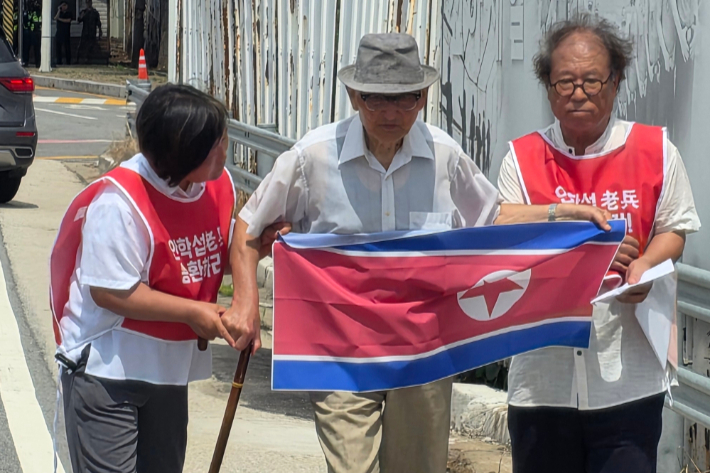 20일 오전 경기도 파주시 통일대교 남단에서 북한 송환을 요구한 비전향장기수 안학섭 씨(가운데)가 인공기를 펼쳐 들고 있다. 연합뉴스