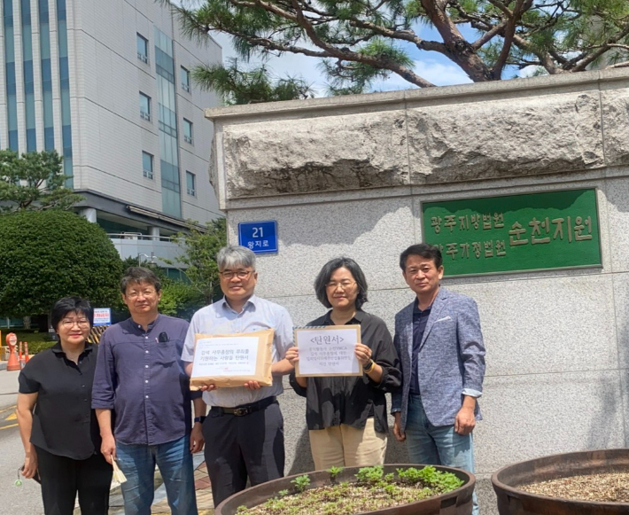 김석 사무총장(가운데) 등이 순천 법원 입구에서 탄원서를 들고 있다.  '김석 사무총장의 무죄를 기원하는 사람들' 제공