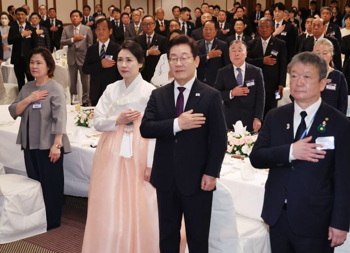 이재명 대통령과 김혜경 여사가 23일 일본 도쿄의 한 호텔에서 열린 재일동포 오찬 간담회에서 국기에 경례하고 있다. 연합뉴스