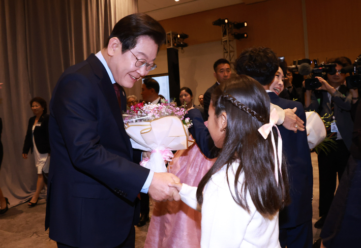 이재명 대통령과 김혜경 여사가 24일(현지시간) 미국 워싱턴DC의 한 호텔에서 열린 동포 만찬 간담회에 참석해 화동으로부터 꽃다발을 받고 있다. 연합뉴스