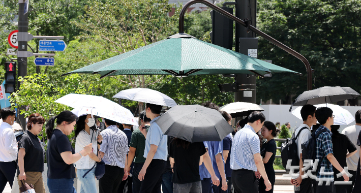 서울 광화문광장에서 양산을 쓴 시민들이 발걸음을 옮기고 있다. 박종민 기자